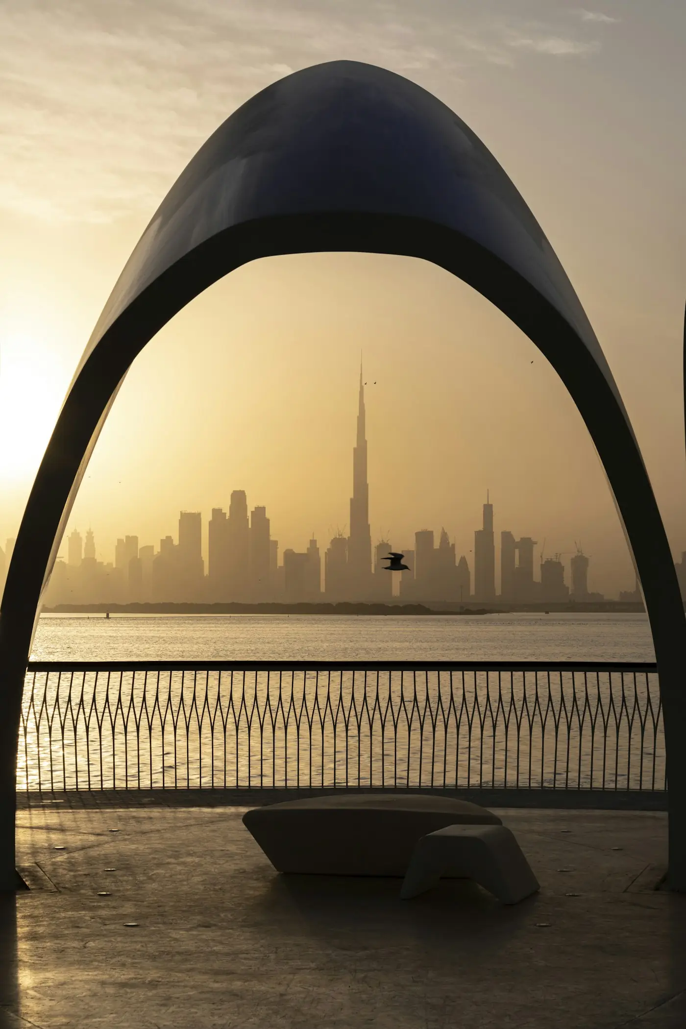 The Dubai skyline at sunset, framed by a curved arch