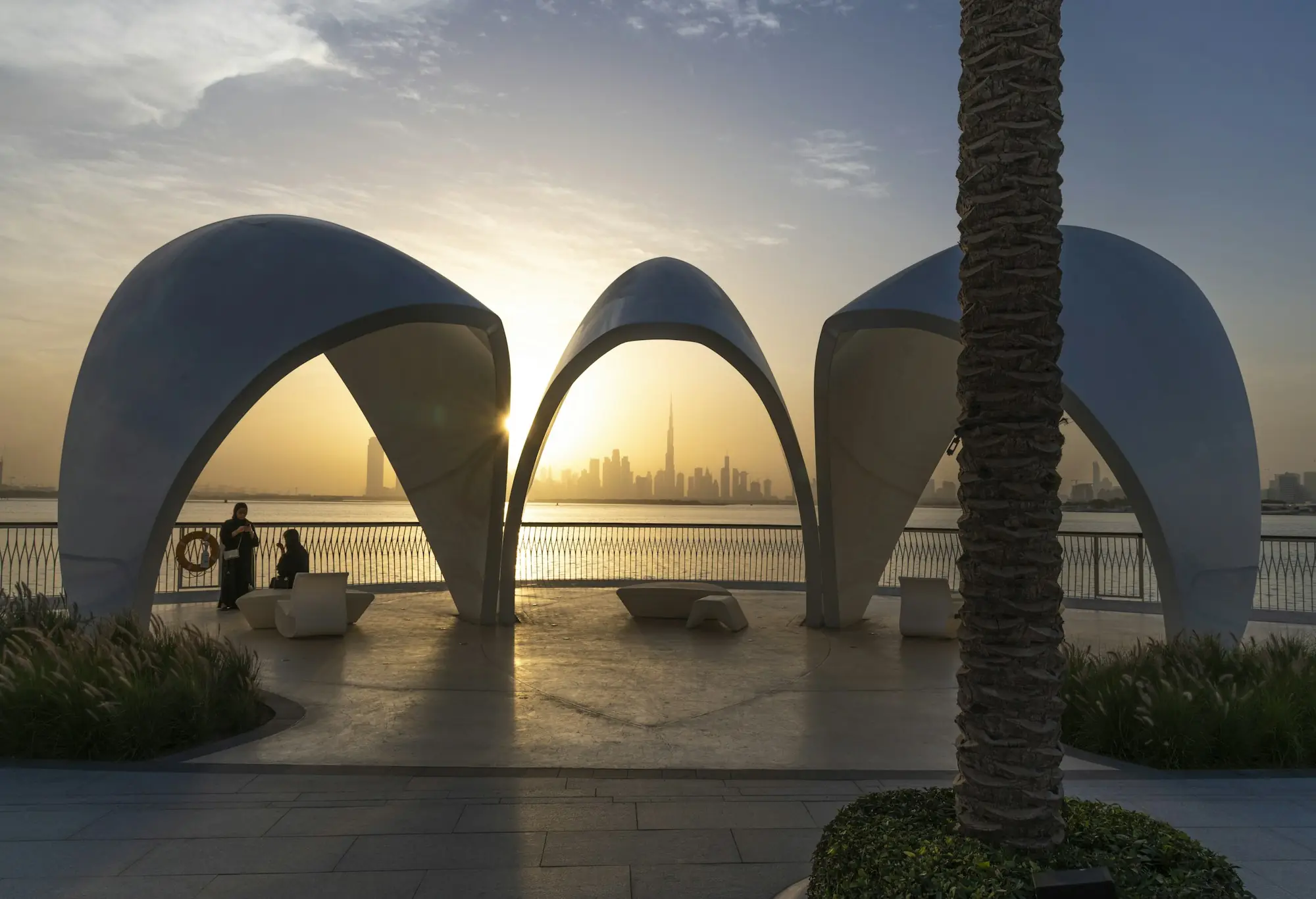 White shell-like pavilions by the water in Dubai at dusk